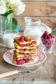 A pile of French toast with hazelnut & chocolate spread and fresh raspberries, served with milk