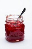 A jar of strawberry jam on a white surface