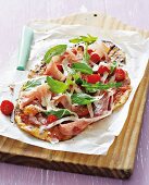 Pan pizza with tomatoes, raw ham, rocket and Parmesan