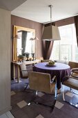 Console table and retro armchairs at round table in dining area