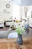 Wiesenblumenstrauß in schwarz-weißer Vase auf rustikalem Holztisch