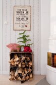 Firewood in wooden crate and small Christmas tree next to white tiled stove