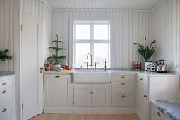 Ceramic sink and wood-clad walls in Swedish country-house kitchen