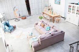 View from gallery down into comfortable lounge and dining area with grey concrete floor