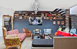 Verschiedene Sitzmöbel um Couchtisch, Goldrahmenspiegel und alte Holzkisten über Raumteilerwand im Wohnraum
