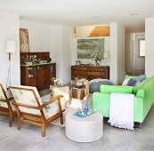 Neon-green sofa, armchairs and antique furnishings in open-plan interior