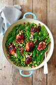 Chicken thights with shallots, broad beans, peas, mangetout and raisins