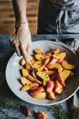 A Woman is mixing sugar sprinkled peaches