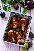 Chicken drumsticks with bacon and plums