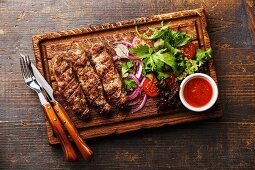 Grilled Lula kebab lamb with onions, salad and tomato spicy sauce Satsebeli on wooden board