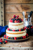 A two-tier semi-naked cake with vanilla cream and fresh berries