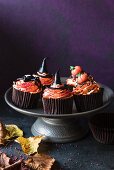 Halloween cupcakes with orange buttercream and assorted fondant decorations on a cake stand