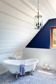Free-standing bathtub and blue accent wall in attic bathroom