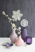 Flowering branches in vases with structured surfaces in various shades of pink and purple