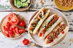 Selbst gemachte Hot Dogs mit gebratenen Zwiebeln, Tomaten und Gurken, serviert mit Zutaten