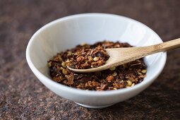 Chilli flakes with a wooden spoon in a bowl