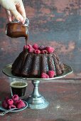 Double chocolate cake with raspberries and chocolate sauce baked into a bundt tin