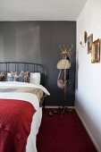Metal bed and old coat stand against black wall