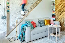 Restored wooden staircase, couch in living room and sliding door made from reclaimed wood