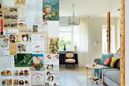 Raumteilerwand mit alten Zeitschriften tapeziert; Blick in Wohnbereich