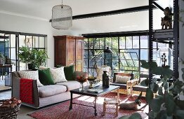 Couch, houseplants and tilted metal windows in eclectic lounge