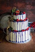 A three-tier wedding cake with forest berries, vanilla buttercream and purple chocolate ganache