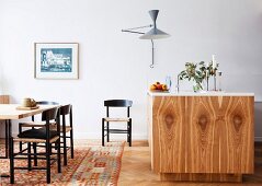 Island counter with wood-grained front and dining area on patterned carpet