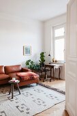 Antique table, vintage office chair, plant stand and leather couch in living area