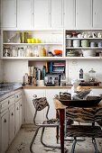 Open-fronted shelves and dining area in white country-house kitchen