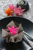Origami flowers on black plate with raised pattern