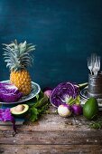 A still life with red cabbage, pineapple, avocado and turnips on a wooden table