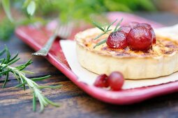 A small cheese quiche with poached red grapes and rosemary
