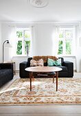 Runder Couchtisch und schwarzes Sofa im hellen Wohnzimmer