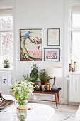 Marmor-Couchtisch mit weißem Wiesenblumenstrauß in Wohnbereich mit Blumenbank und schwarz gerahmten Bildern