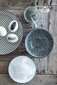 Eggs painted with feather on patterned plate and bowls on wooden surface