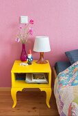 Garden gnome on bright yellow bedside table against pink wall