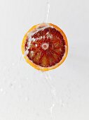 Half a blood orange being sprayed with a jet of water