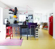 Various bar stools in colourful open-plan kitchen with yellow floor