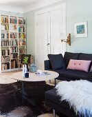 Wohnbereich mit schwarzer Couch, weißer Flügeltür und Bücherregal