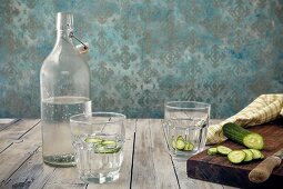 Glas Gurkenwasser, Wasserflasche und frische Gurke