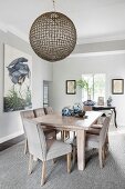 Ceramic pots on chunky dining table and upholstered chairs in elegant interior