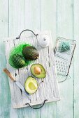 Fresh avocados, whole and sliced, on a wooden board