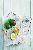 Frische Avocados, ganz und aufgeschnitten, auf Holzbrett