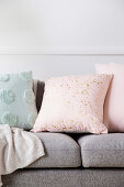 Pastellfarbene Kissen mit Punkten und Tupfen auf grauem Sofa