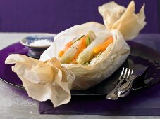 White asparagus wrapped in paper with carrots and ginger