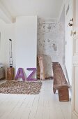 Schlafzimmer mit Leder-Teppich, lila Deko-Buchstaben und Ethno-Holzstuhl