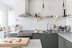 Graue Einbauküche mit Edelstahlabzugshaube und Wandboards an weißer Fliesenwand
