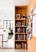 Open shelf with books and accessories and a view of an open living area
