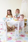 Three toddlers in children's room with white children's table and toys