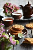 Coconut cookies stacked on plate, tea and flowers in the background